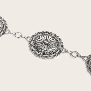 Détail de la chaîne de taille rétro avec disques en métal argenté et motifs gravés