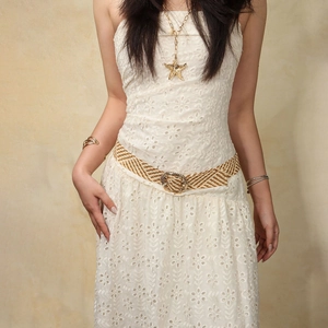 Detalle de vestido de encaje blanco con cinturón dorado trenzado y collar de estrella de mar
