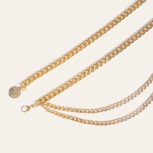 Detail einer goldenen mehrlagigen Taillenkette mit Münzanhänger und Karabiner