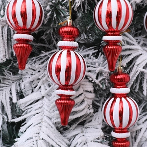 Adornos navideños en espiral rojo y blanco colgados en una rama nevada para decoración