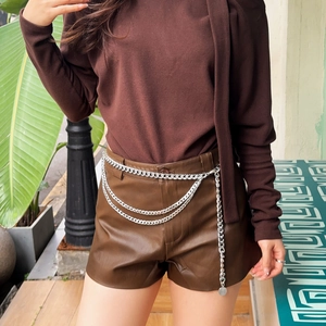 Detail einer silbernen mehrlagigen Metall-Taillenkette mit drei Lagen auf Lederhose