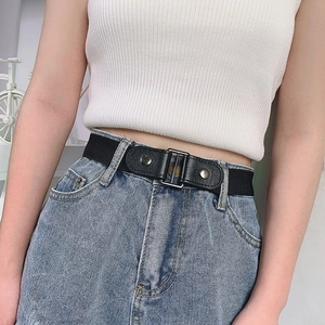 Detail view of a black elastic buckle-free belt on blue denim jeans for women