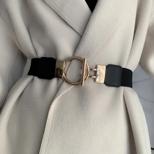 Close-up of black elastic waist belt with a golden ring and toggle buckle on white coat