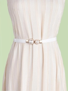 Detail of slim elastic waist belt with double pearls and gold buckle on a dress