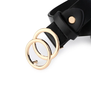 Detail of the golden double-ring buckle on a slim black leather belt for jeans