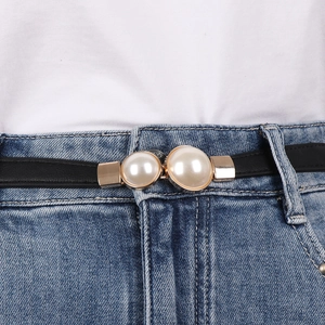 Close-up of elegant gold-rimmed double pearl buckle on a black slim leather belt for women