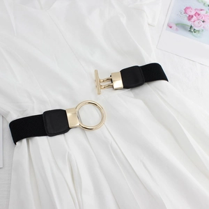 Detail of minimalist gold round ring and T-bar buckle on a black elastic waist belt