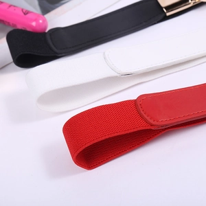 Détail des ceintures élastiques en rouge, blanc et noir avec des boucles métalliques