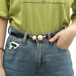 Close-up of black elastic belt with golden alloy buckle and two large pearl decorations
