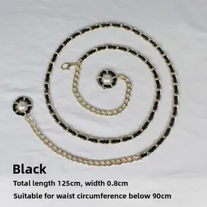 Détail d'une ceinture chaîne dorée entrelacée de cuir noir et breloques camélia