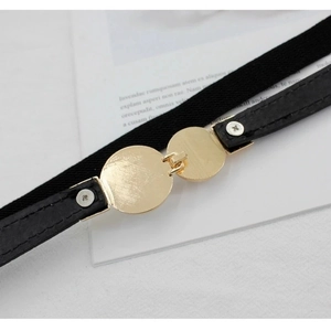 Detailed macro view of dual gold circular metal buckles on a black elastic thin belt