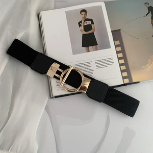 Detail view of the black elastic wide belt with a golden circular buckle on a magazine