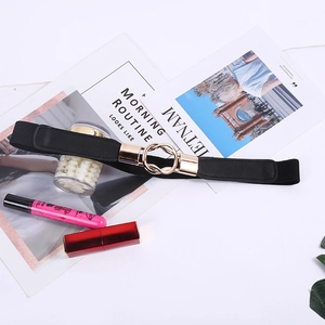Détail d'une fine ceinture élastique noire avec boucle dorée à double anneau sur décor