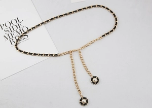 Détail de la ceinture chaîne dorée entrelacée de cuir noir et pendentifs fleurs en perles