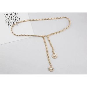 Détail de la ceinture chaîne en métal doré avec cuir blanc et pendentif perle camélia