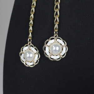 Détail d'une chaîne de taille dorée avec pendentifs en perles sur fond en tissu noir