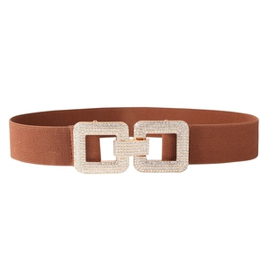 Détail de la boucle géométrique dorée sertie de strass sur ceinture élastique brune