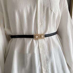 Detail of elegant gold chain buckle with pearls on a slim black leather waist belt