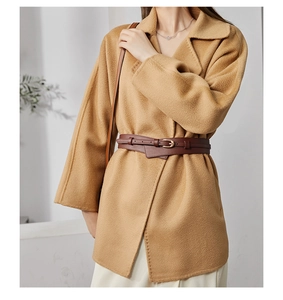Detail of camel wool coat with dark brown leather belt and minimalist lapel design