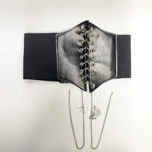 Détail d'une large ceinture corset élastique avec cuir à lacets et chaînes papillons