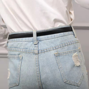 Rear view of a slim black leather belt styled on light blue ripped jeans for women