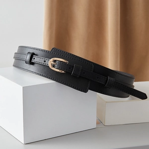 Close-up of black wide leather waist belt with gold horseshoe buckle on white props