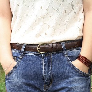 Detail of slim dark brown leather belt with vintage metal buckle on blue jeans