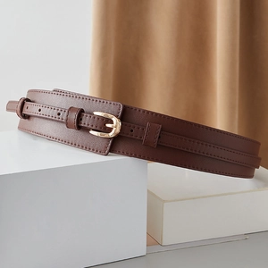 Detail of dark brown double-layer leather waist belt with polished gold buckle and stitching