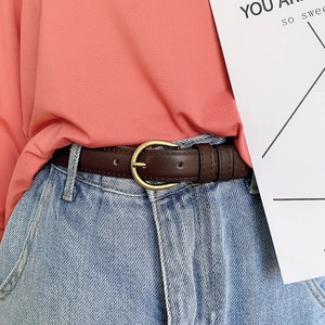 Close-up of a slim dark brown leather belt with a gold D-buckle on blue denim jeans