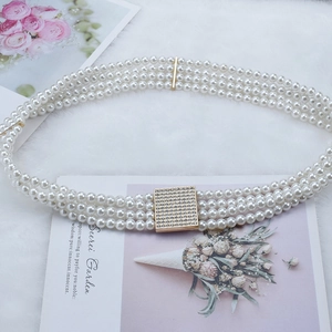 Dettaglio della cintura a tre file di perle con fibbia dorata con strass per abiti eleganti