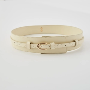 Detail of a beige wide faux leather waist belt featuring a gold horseshoe buckle closure