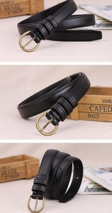 Close-up of black retro leather belt with brass buckle displayed on rustic background