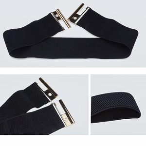 Detail of black wide elastic waist belt featuring a polished gold interlocking metal buckle