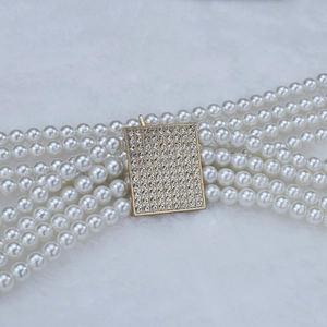Dettaglio di un'elegante cintura a quattro file di perle con fibbia dorata ricoperta di strass