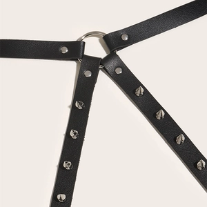 Detail of black leather punk body harness with silver rings and pointed metal rivets