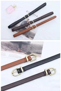 Trois ceintures en cuir noir et marron avec boucles dorées en fer à cheval sur un magazine