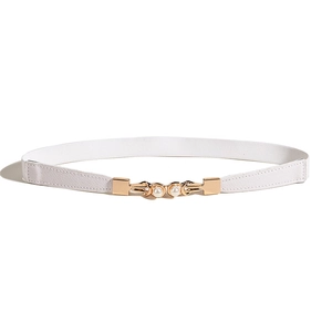 Détail d'une boucle dorée avec perles blanches sur une fine ceinture élastique pour femme