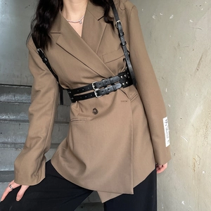 Detailed view of punk style black faux leather harness straps over a brown blazer vest