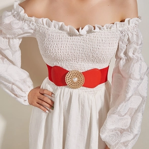 Détail de la ceinture élastique rouge avec boucle ronde dorée et perle centrale