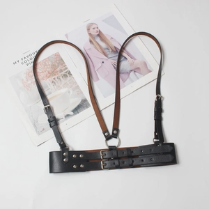 Detail view of a black leather harness belt with silver metal buckles and O-rings
