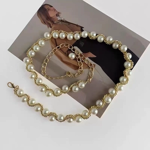 Vue détaillée d'une chaîne de taille dorée avec perles blanches et fermoir mousqueton chic