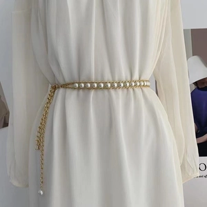 Détail d'une ceinture chaîne dorée élégante avec trois rangées de perles sur robe
