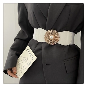 Détail de la ceinture élastique blanche avec boucle ronde dorée et perle sur veste