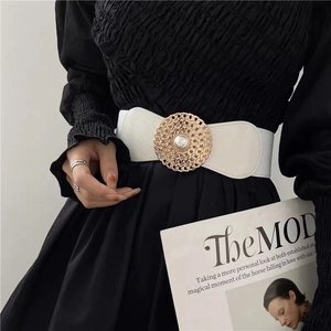 Détail de la ceinture élastique blanche avec boucle chaîne dorée et perle centrale