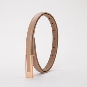 Détail d'une ceinture fine en cuir kaki avec boucle dorée et surpiqûres de qualité