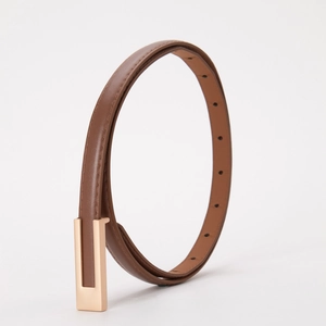 Détail d'une ceinture minimaliste marron foncé avec boucle métallique rectangulaire dorée