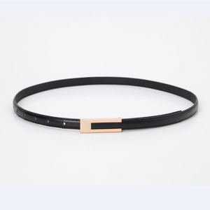 Détail de la fine ceinture en cuir noir avec une boucle rectangulaire dorée épurée