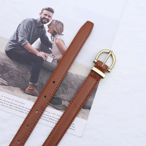 Detail of slim brown PU leather belt featuring a golden horseshoe buckle and fine stitching