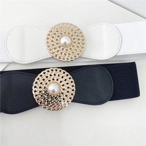 Détail de ceintures élastiques noires et blanches avec boucles dorées et perles centrales