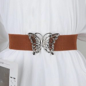 Détail d'une ceinture élastique marron caramel avec une grande boucle papillon en métal argenté